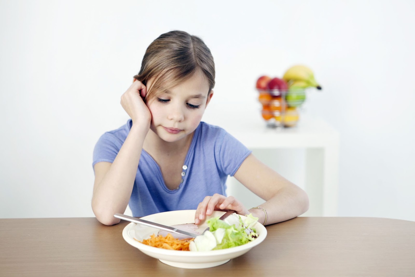 Bir kız çocuğu masada oturuyor ve yemek yemiyor. çocuklarda yeme bozuklukları kavramı