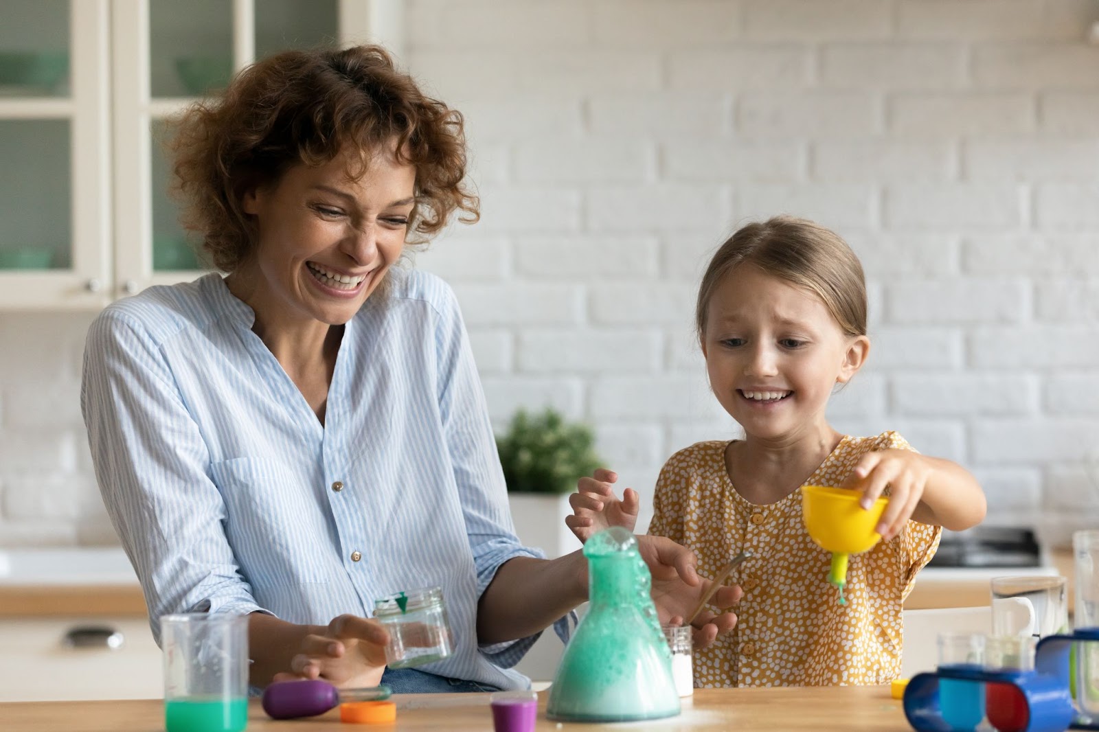 Heyecanlı duygusal ebeveyn anne kız çocuk ev mutfağında kendi yaptıkları kimyasal testin sonucunu izliyor.