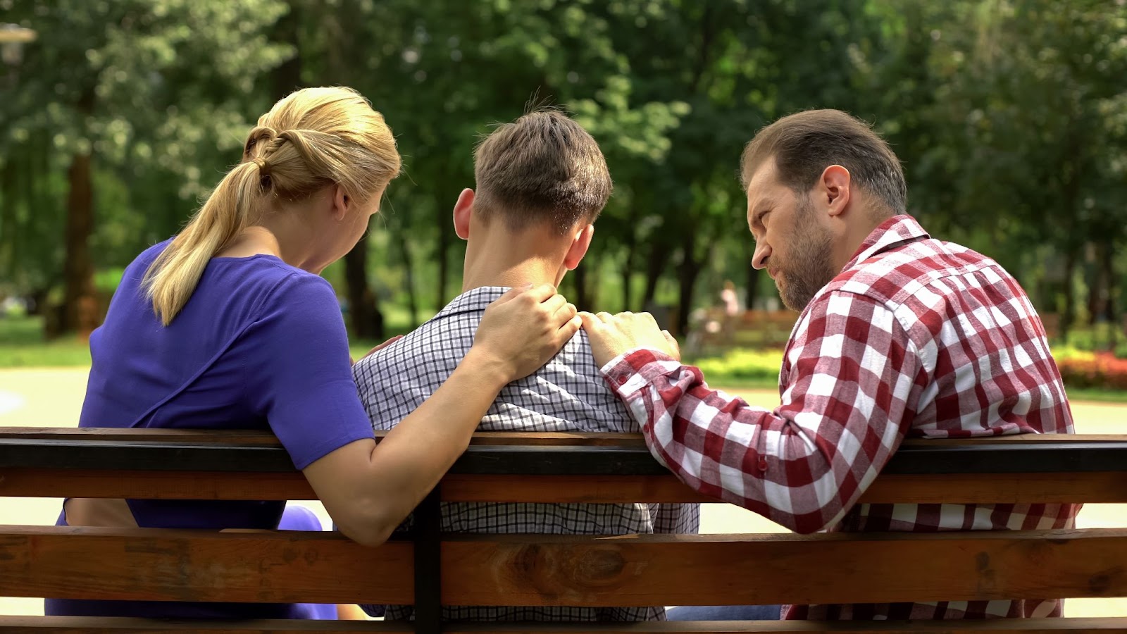 Bakım anne ve baba destek üzgün genç oğlu parkta bankta oturan, kriz